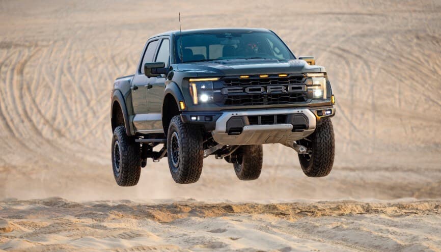 Ford F-150 springt über Sanddünen in einer dynamischen Aktion, mit einer klaren Sicht auf die Vorderansicht