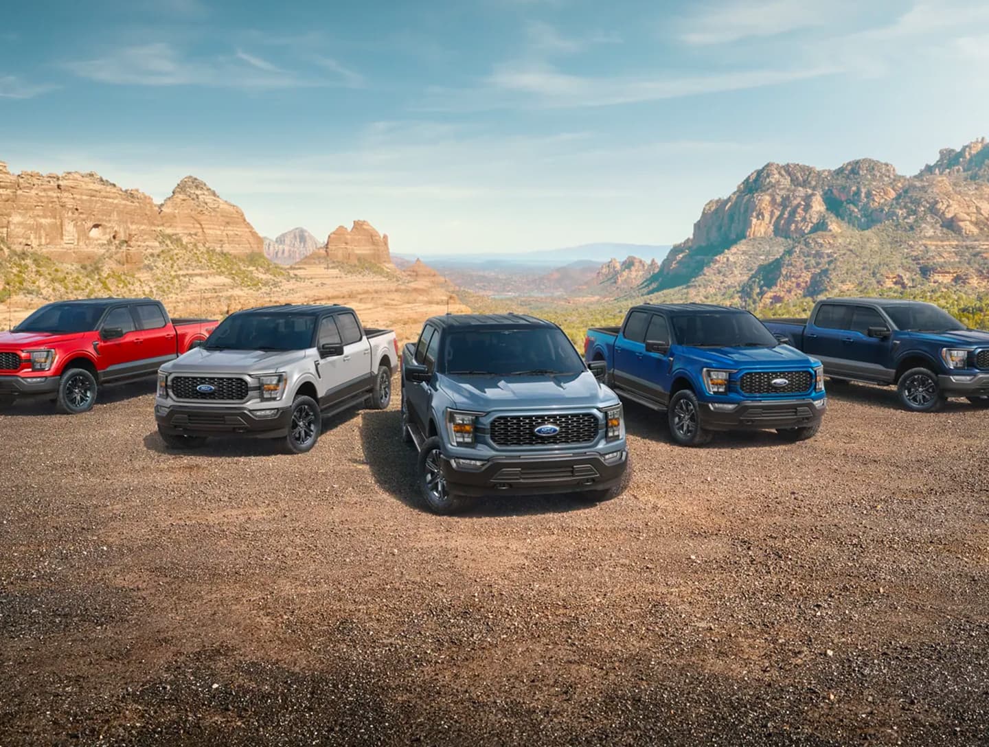 Fünf Ford Pickups in verschiedenen Farben stehen vor einer beeindruckenden Berglandschaft