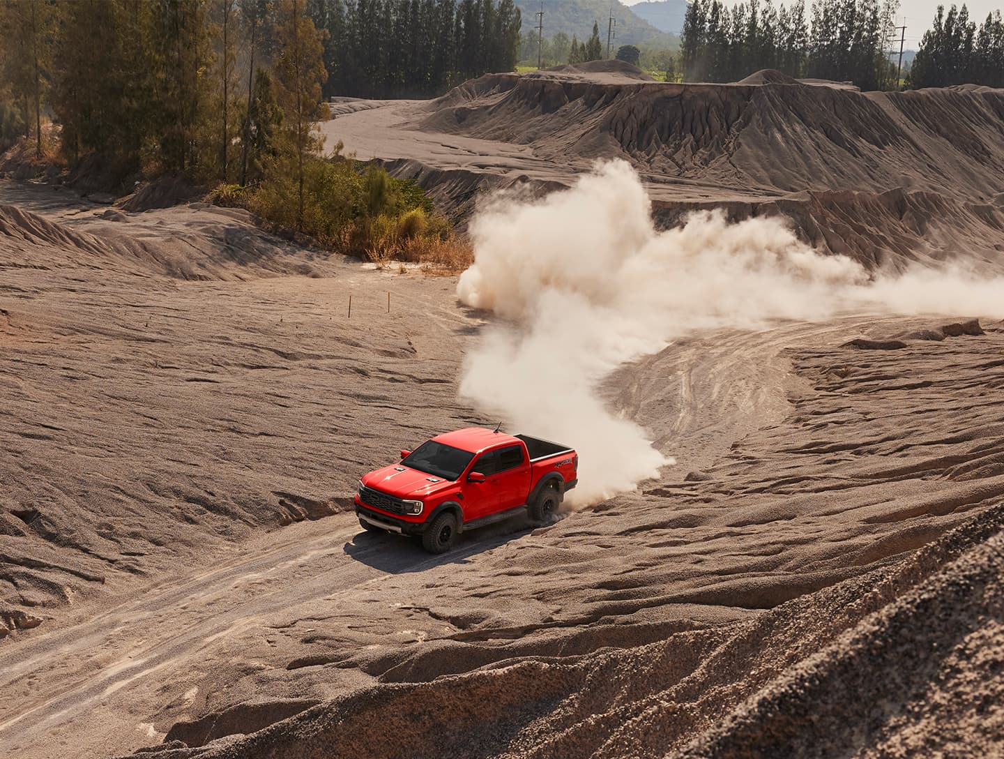Ford Pickup fährt über unebenes Terrain mit Staubwolken im Hintergrund