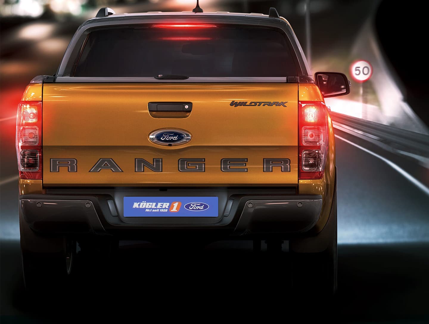 Heckansicht eines gelben Ford Ranger Wildtrak auf einer Straße bei Nacht mit Rücklichtern