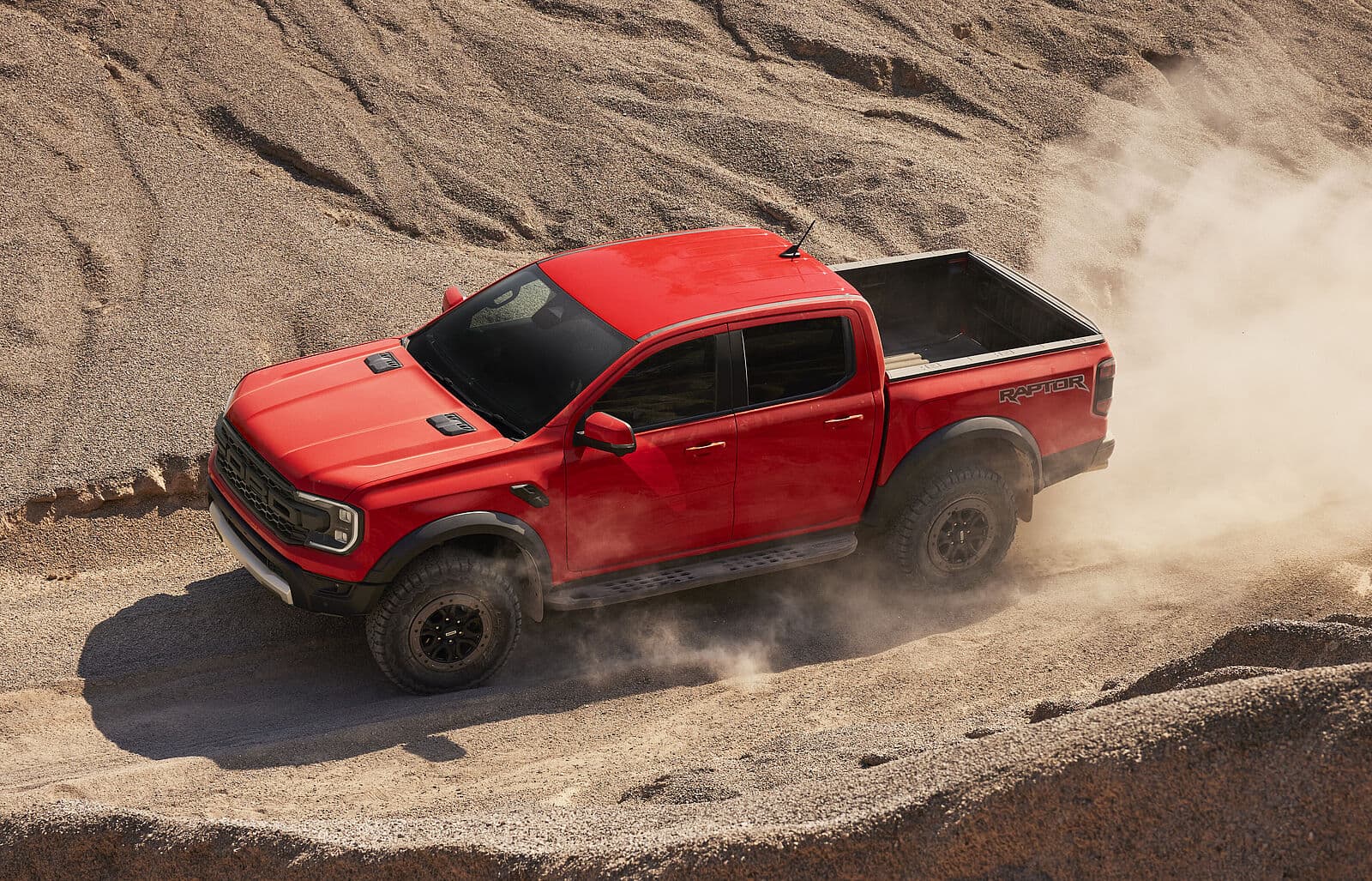 Ford Raptor in Rot, von oben fotografiert, fährt durch sandige Landschaft