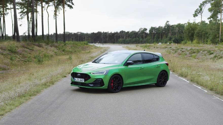 Ford Focus 2025 in auffälligem Grün, seitliche Ansicht auf einer Landstraße mit Bäumen im Hintergrund